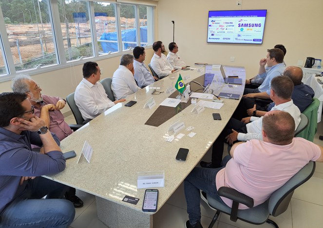 Foto mostra a um grupo de pessoas, uma apresentação em um telão sobre operação de uma fábrica