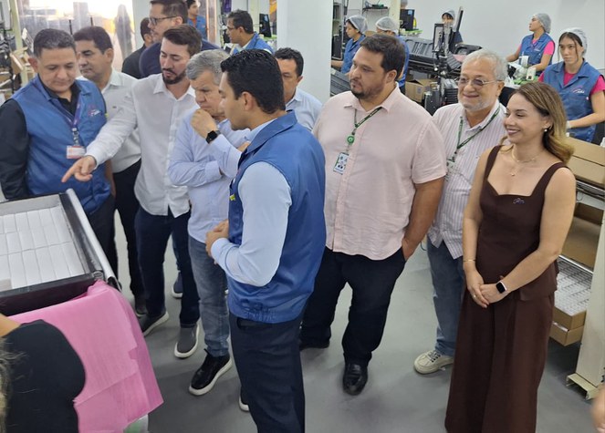 Foto mostra grupo de pessoas em uma linha de produção fabril