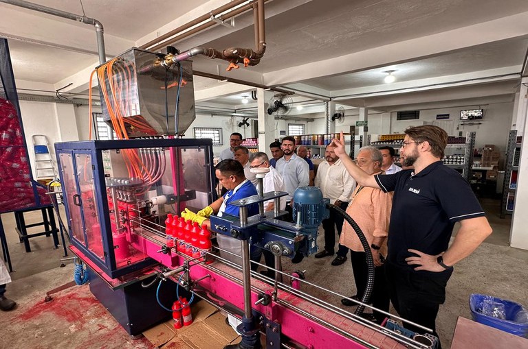 Pessoas olhando uma linha de produção de envasamento de cera líquida