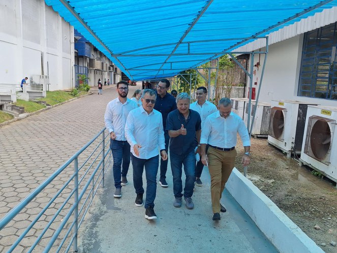 Foto mostra homens caminhando com uma lona azul como proteção