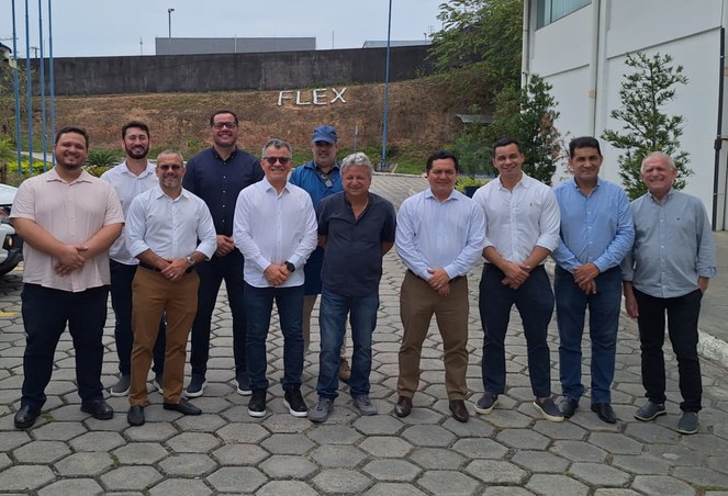 Foto mostra homens posando para sessão de foto, com um muto e um letreiro ao fundo