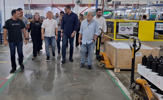 Foto mostra um grupo de pessoas em visita a um fábrica