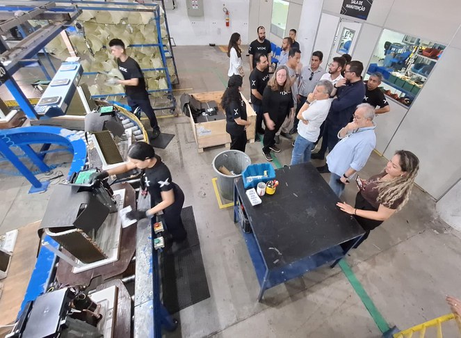 Foto mostra grupo de pessoas em visita a um fábrica