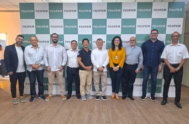 Foto mostra um grupo de pessoas em frente a um painel e posando para fotografia