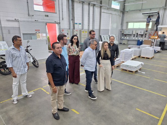 Foto mostra grupo de pessoas dentro de uma fábrica de produtos de papel