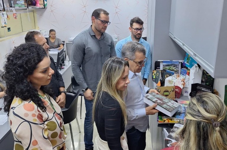 Foto mostra homem segurando um livro, acompanhado de outras pessoas