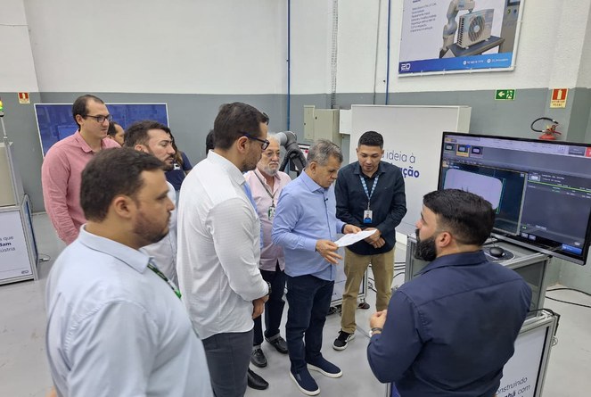 Foto mostra homem olhando para papel, observado por outros homens