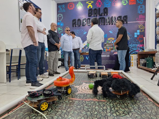 Foto mostra grupo de pessoas em uma sala com projetos de objetos experimentais