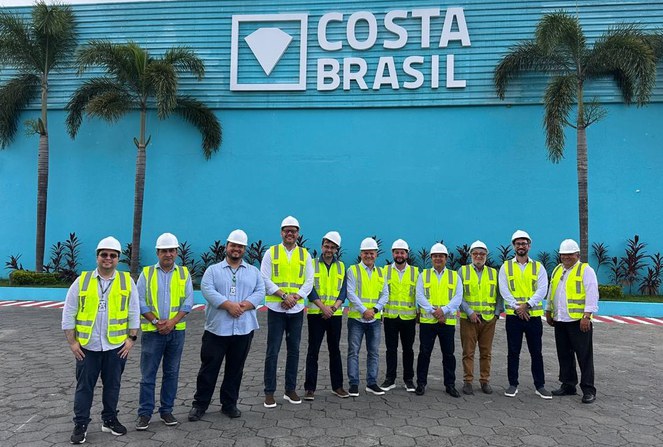 Foto mostra pessoas posando para foto, com parede azul ao fundo