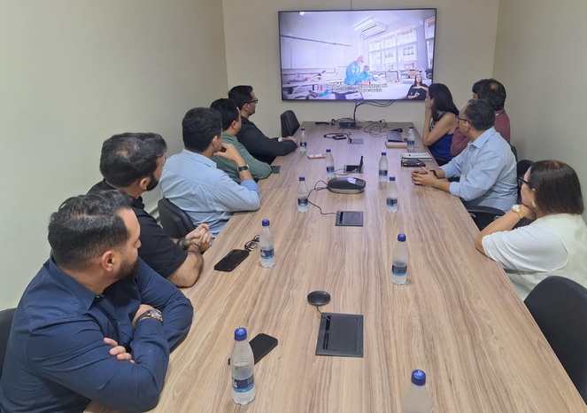 Foto mostra pessoas olhando para uma apresentação feita num aparelho de TV