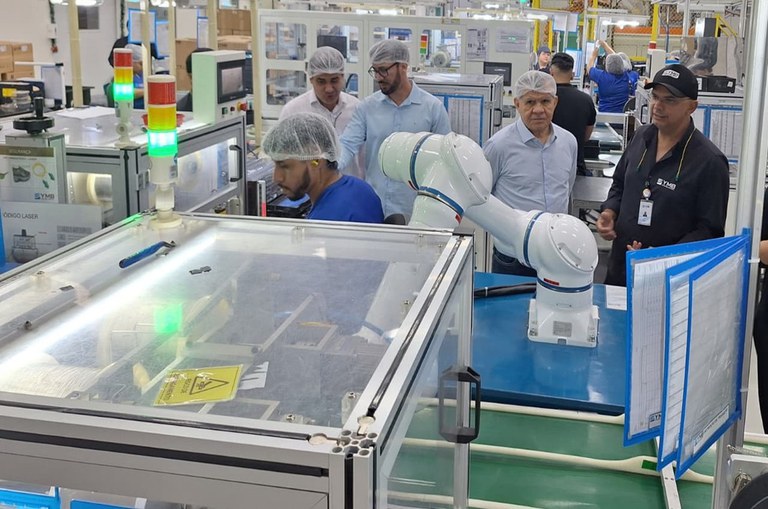 Foto mostra homens de touca olhando para maquinários