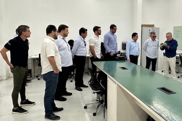 Foto mostra homem mostrando um objeto a grupo de pessoas