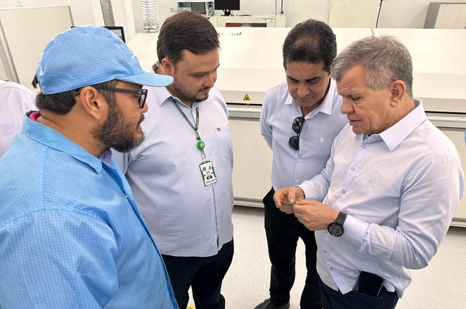 Foto mostra homens olhando para um objeto