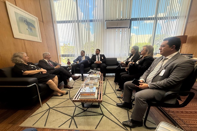 Foto mostra pessoas sentadas e conversando numa reunião