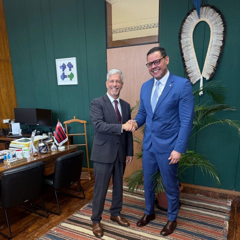 Foto mostra dois homens de blazer apertando as mãos e posando para foto