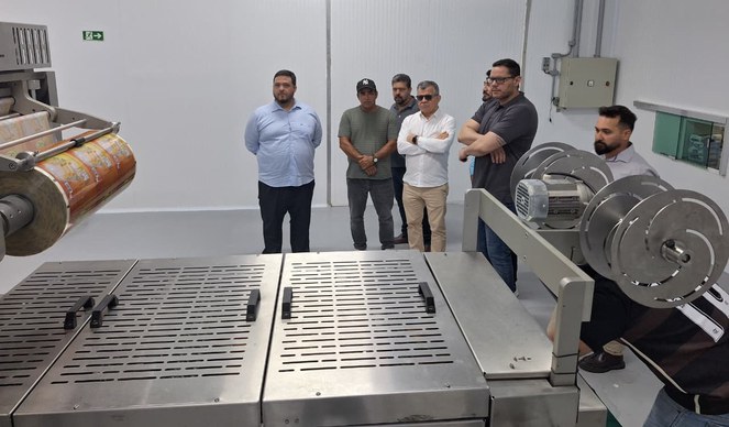 Foto mostra grupo de homens olhando para uma máquina