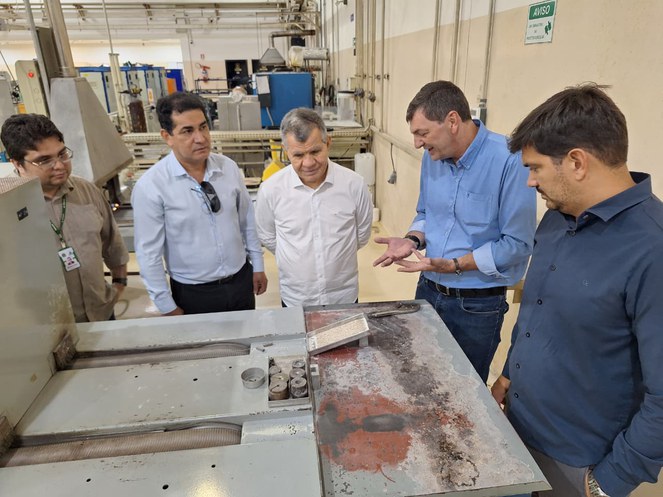 Foto mostra homens olhando para um objeto