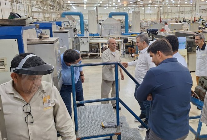 Foto mostra homens em uma fábrica