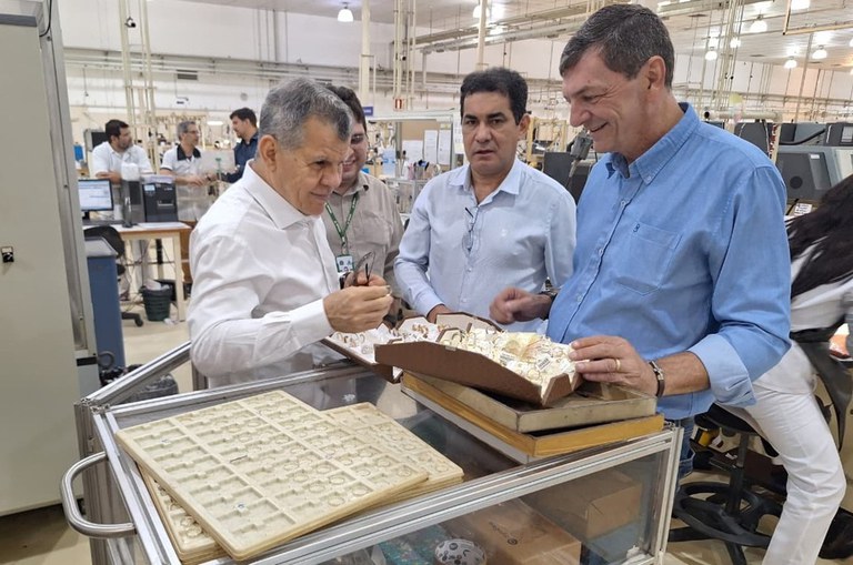 Foto mostra homem segurando um anel, observado por outros homens