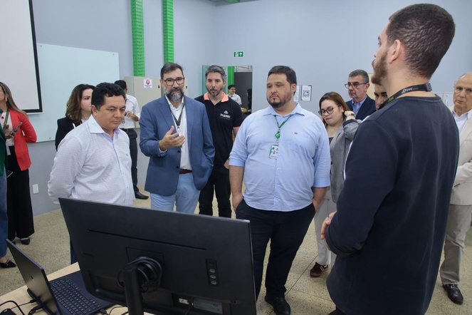 Foto mostra pessoas olhando para um computador