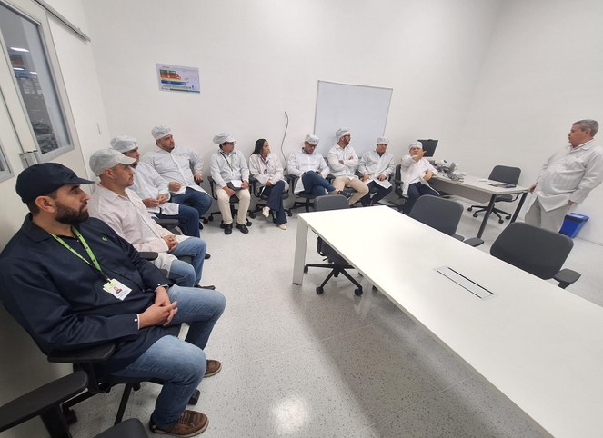 Foto mostra um grupo de pessoas de bata branca e azul numa reunião