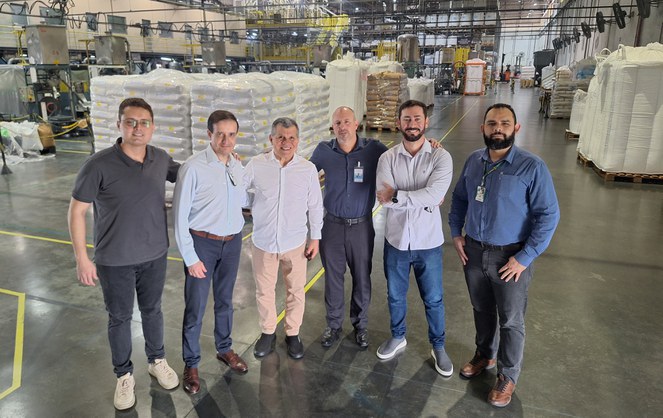 Foto mostra grupo de homens com saco amontoados ao fundo