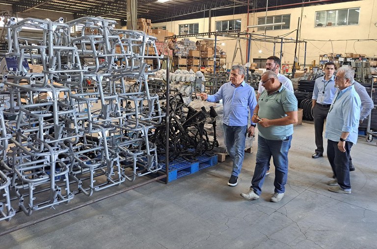 Foto mostra homem de blusa azul apontando para peças de