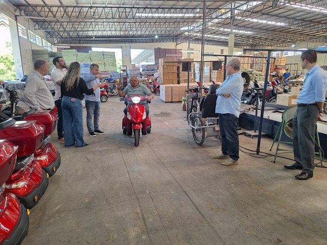 Foto mostra homem num triciclo, observado por grupo de pessoas