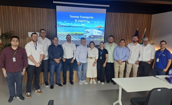 Foto mostra grupo de homens posando para fotografia, com um painel ao fundo