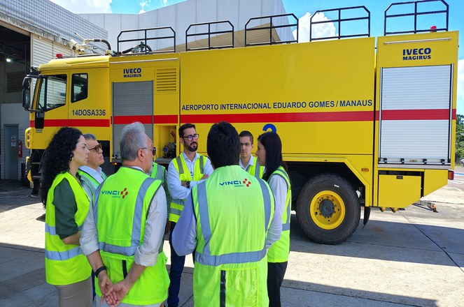 Foto mostra pessoas de jaquetas verdes e um caminhão ao fundo