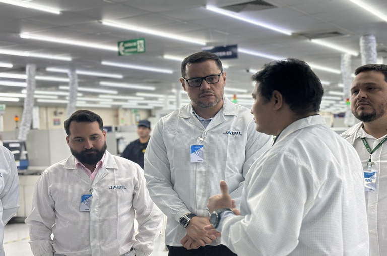 Tres homens vestidos de branco dentro de uma fábrica