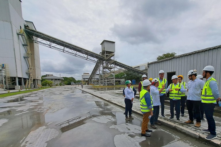 Foto mostra homens com EPIs dentro de uma fábrica