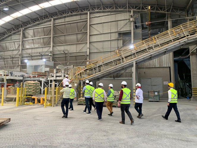 Foto mostra grupo de pessoas vestidas com EPIs em visita a uma fábrica de cimento