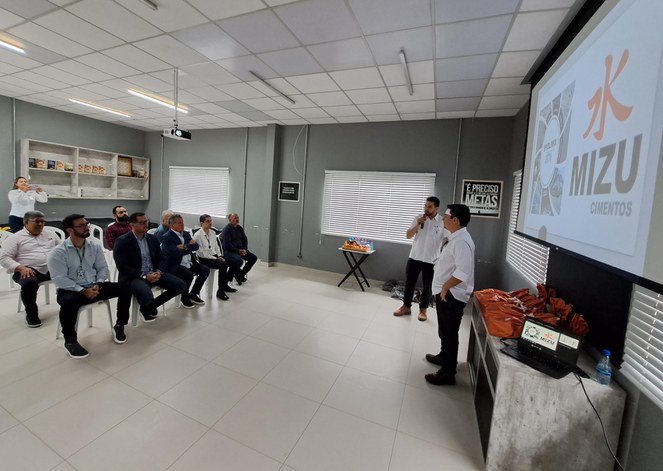 Foto mostra dois homens em pé fazendo uma explicação a um grupo de pessoas