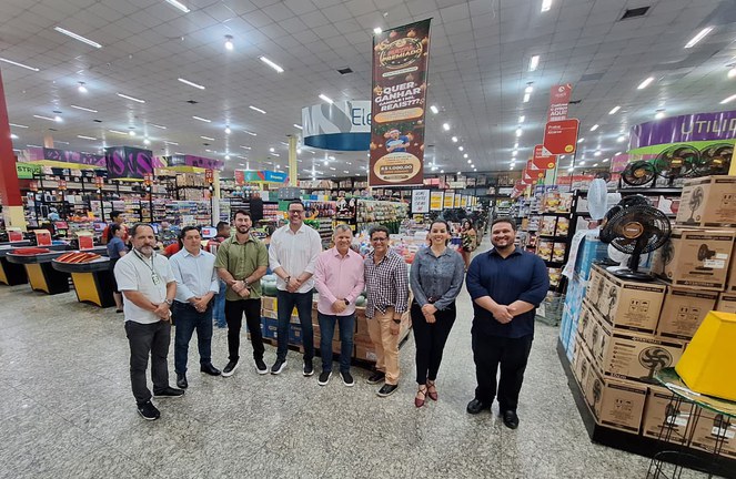 Foto mostra pessoas posando para foto dentro de um estabelecimento comercial