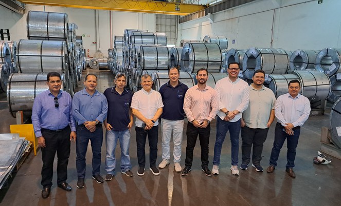 Foto mostra grupo de pessoas posando em frente de produtos de ferro