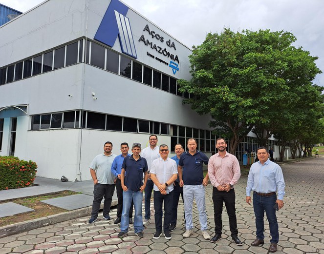 Foto mostra um grupo de homens em frente a uma fábrica