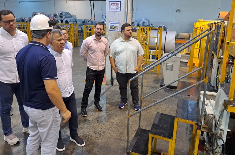 Foto mostra homem de capacete conversando com outro homem de blusa branca