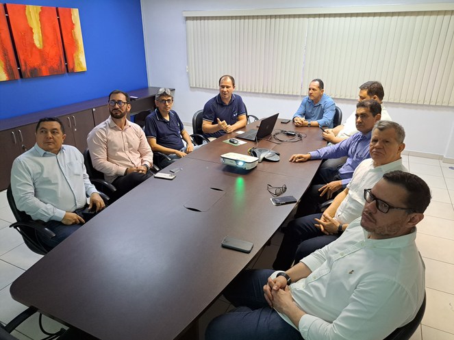 Foto mostra grupo de homens em uma sala fechada durante reunião