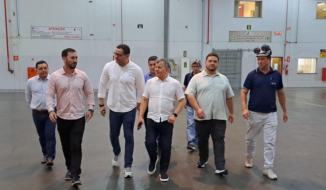 Foto mostra homens caminhando dentro de uma fábrica