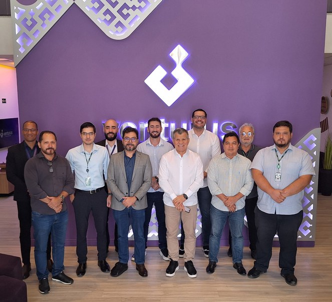 Foto mostra pessoas posando para foto com um painel ao fundo