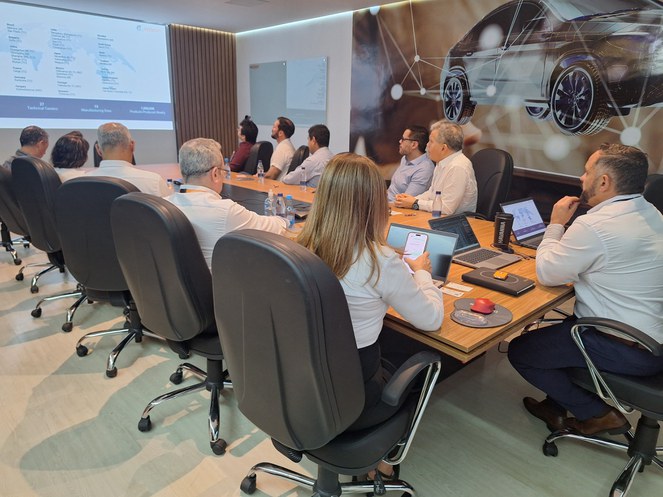 Foto mostra grupo de pessoas olhando para um telão