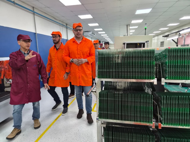 Foto mostra grupo de pessoas visitando linha de produção de medidores de energia