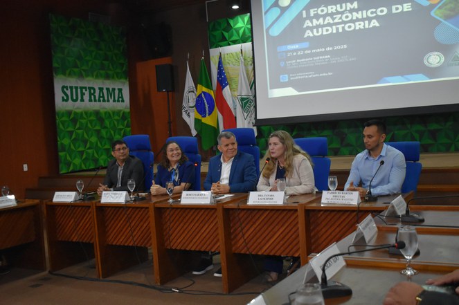 Foto mostra mulher de blazer bege falando ao microfone