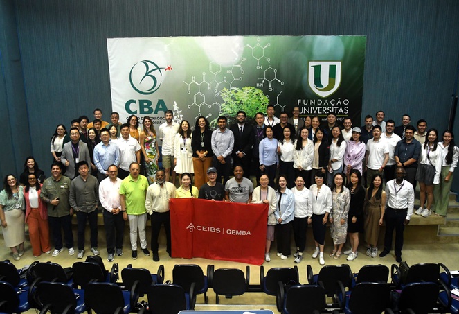 Foto mostra pessoas reunidas em um auditório para um registro fotográfico, com um painel ao fundo
