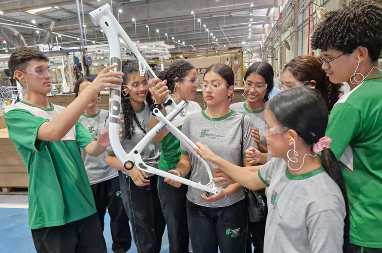 Foto mostra grupo de estudantes segurando uma peça de bicicleta