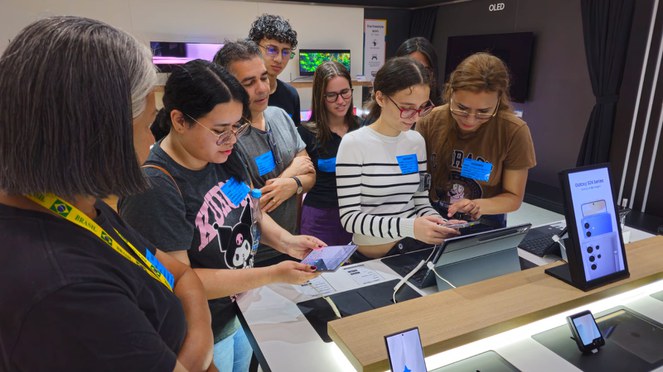 Foto mostra alunos conhecendo uma empresa que produz projetos para celulares