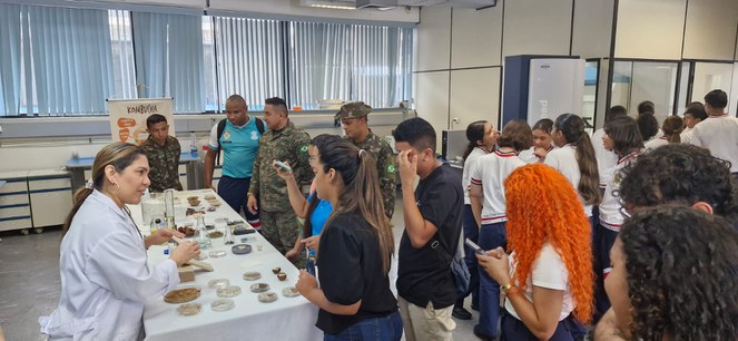 Foto mostra mulher de jaleco branco explicando funcionalidades de um laboratório de pesquisao