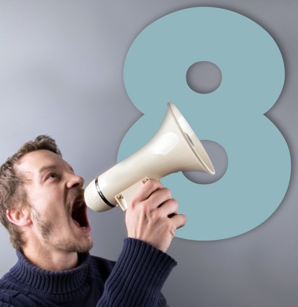Foto de um homem usando um megafone, com um número 8 ao fundo