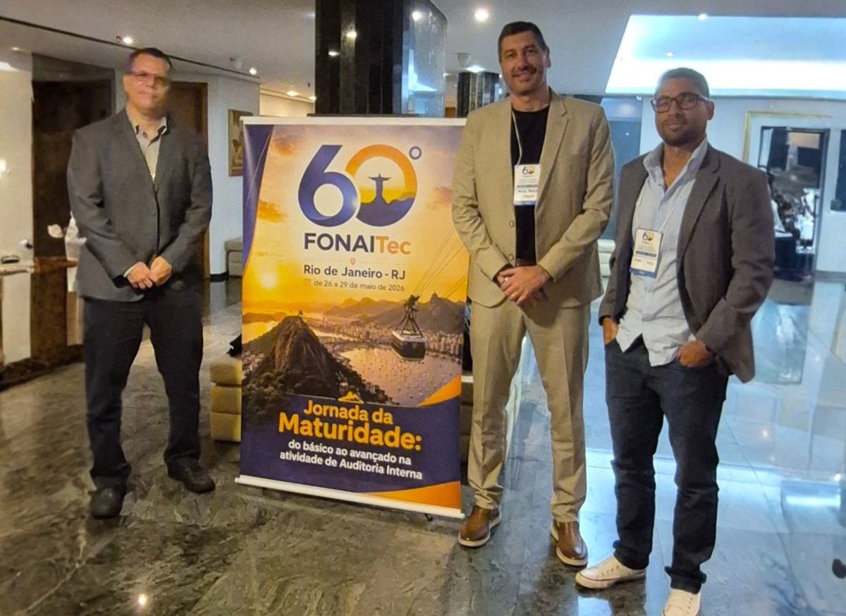 Imagem mostra três servidores da Susep ao lado de banner do evento 60º FONAITec